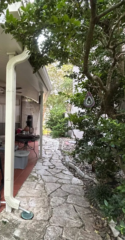 Downspout carried into a drain beside a flagstone patio