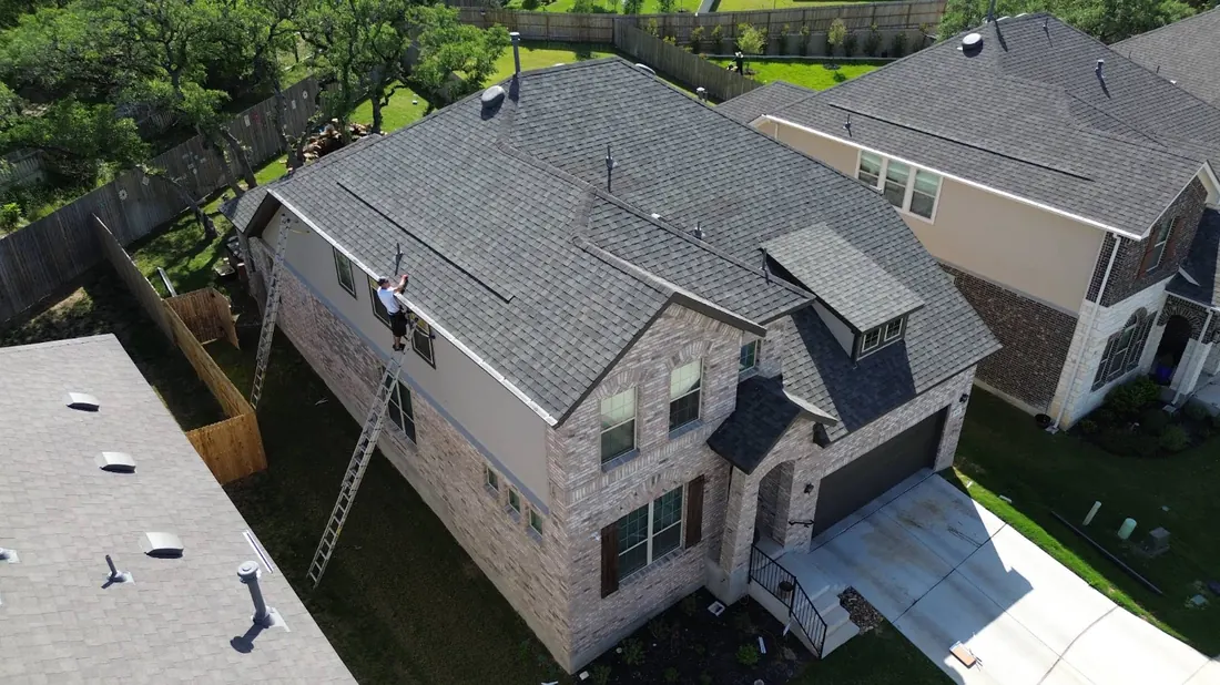 Aerial view of a TX Gutter Expert installer working along a two-story roofline