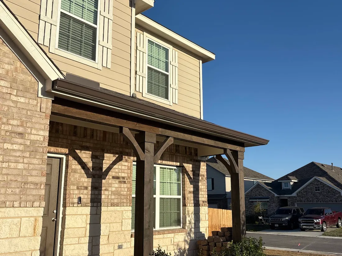 Bronze seamless gutter running along a covered porch with cedar posts
