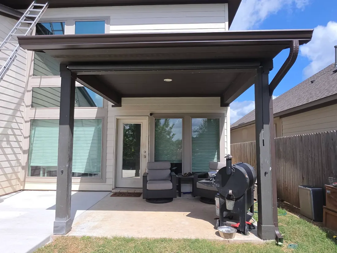 Gutter and downspout on a covered back patio with dark fascia