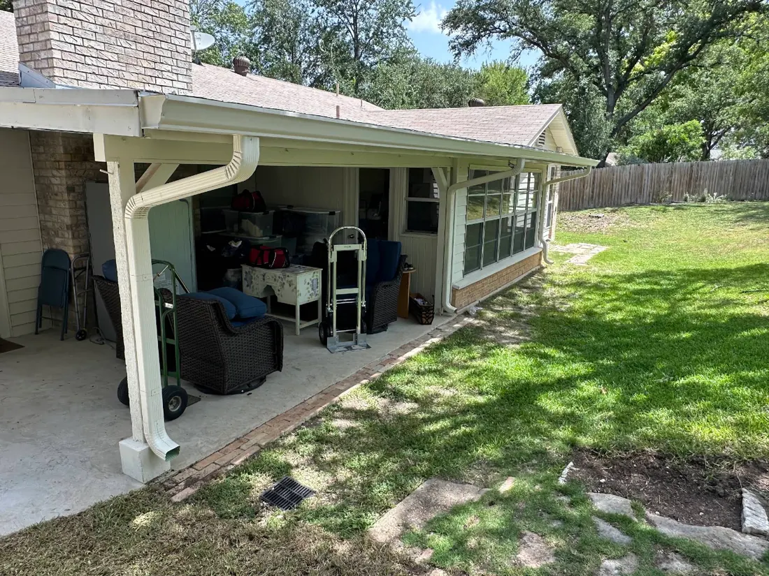 White seamless gutter and downspout along a back porch
