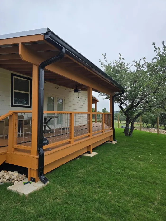 Downspout carried down a covered porch on a hill country home