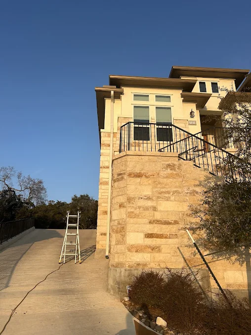 Ladder set against a two-story stone home during a gutter installation