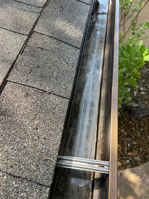 Downspout discharging beside a shingled roof