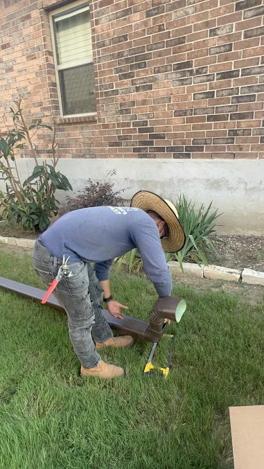 Installer setting downspout drainage beside a brick home