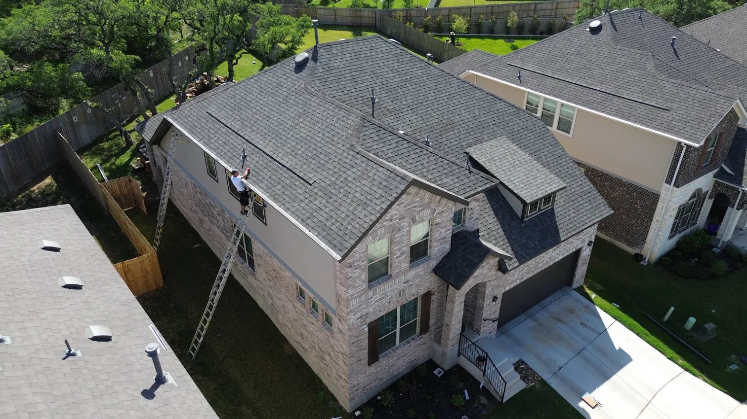 Aerial view of a TX Gutter Expert installer working along a two-story roofline
