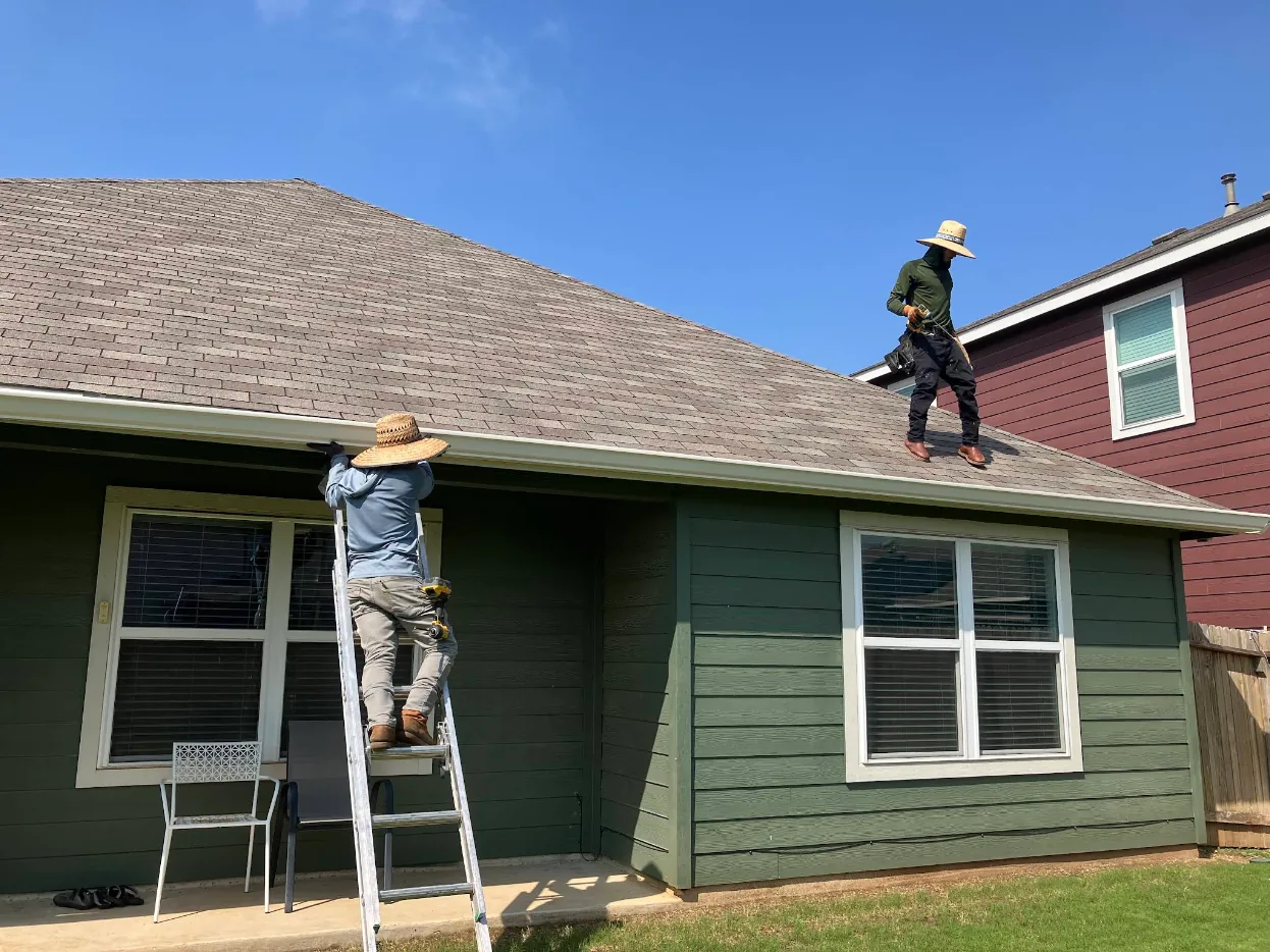 TX Gutter Expert crew installing seamless gutters from a ladder and the roof